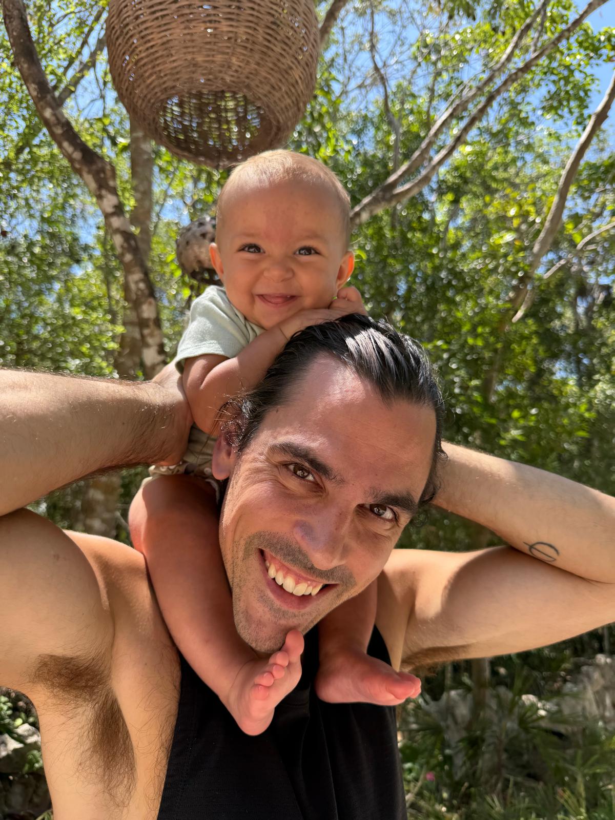 Dan Oig outdoors with his child on his shoulders